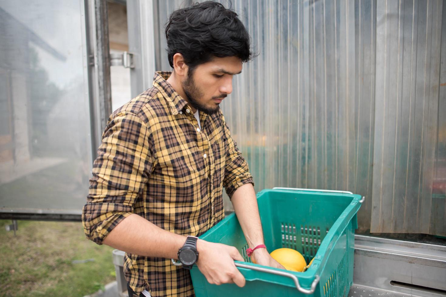 portret van een hipster boer met een doos met fruit te koop op de markt foto