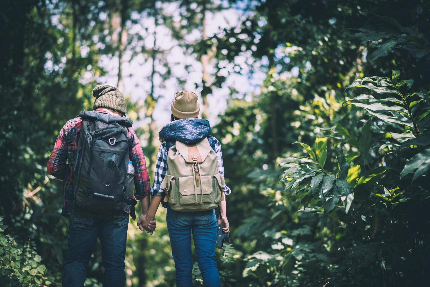 jonge actieve reizigers hand in hand tijdens het wandelen in het bos foto