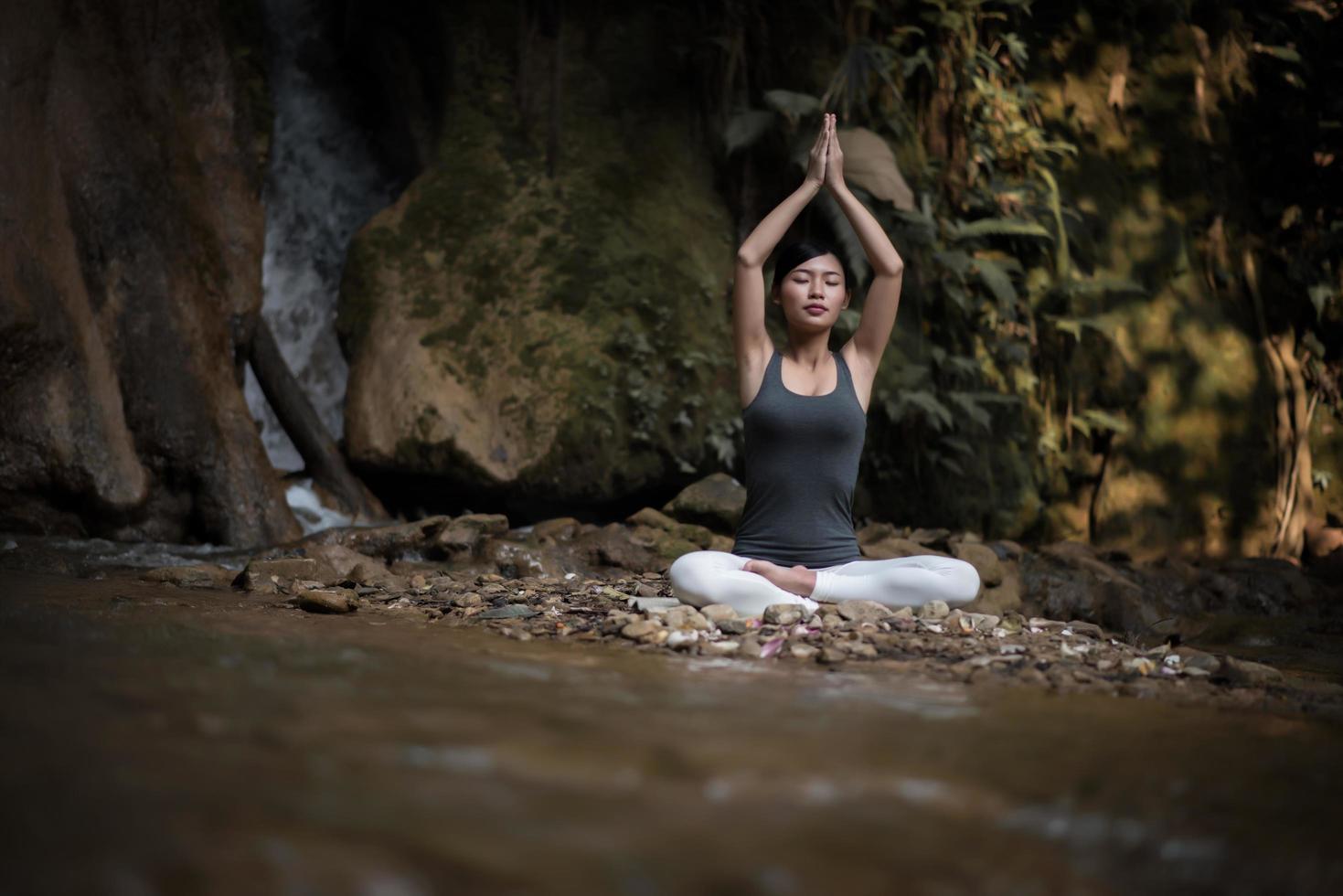 jonge vrouw in een yoga-pose zit in de buurt van een waterval foto