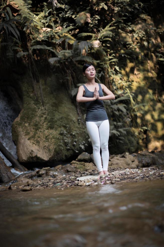 jonge vrouw in een yoga-pose in de buurt van een waterval foto