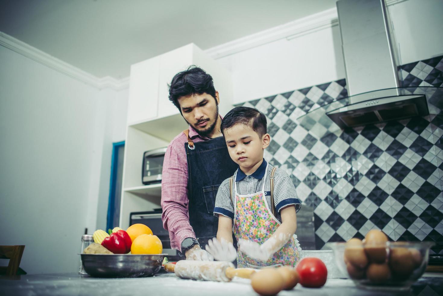 vader leert zijn zoon koken in de keuken foto