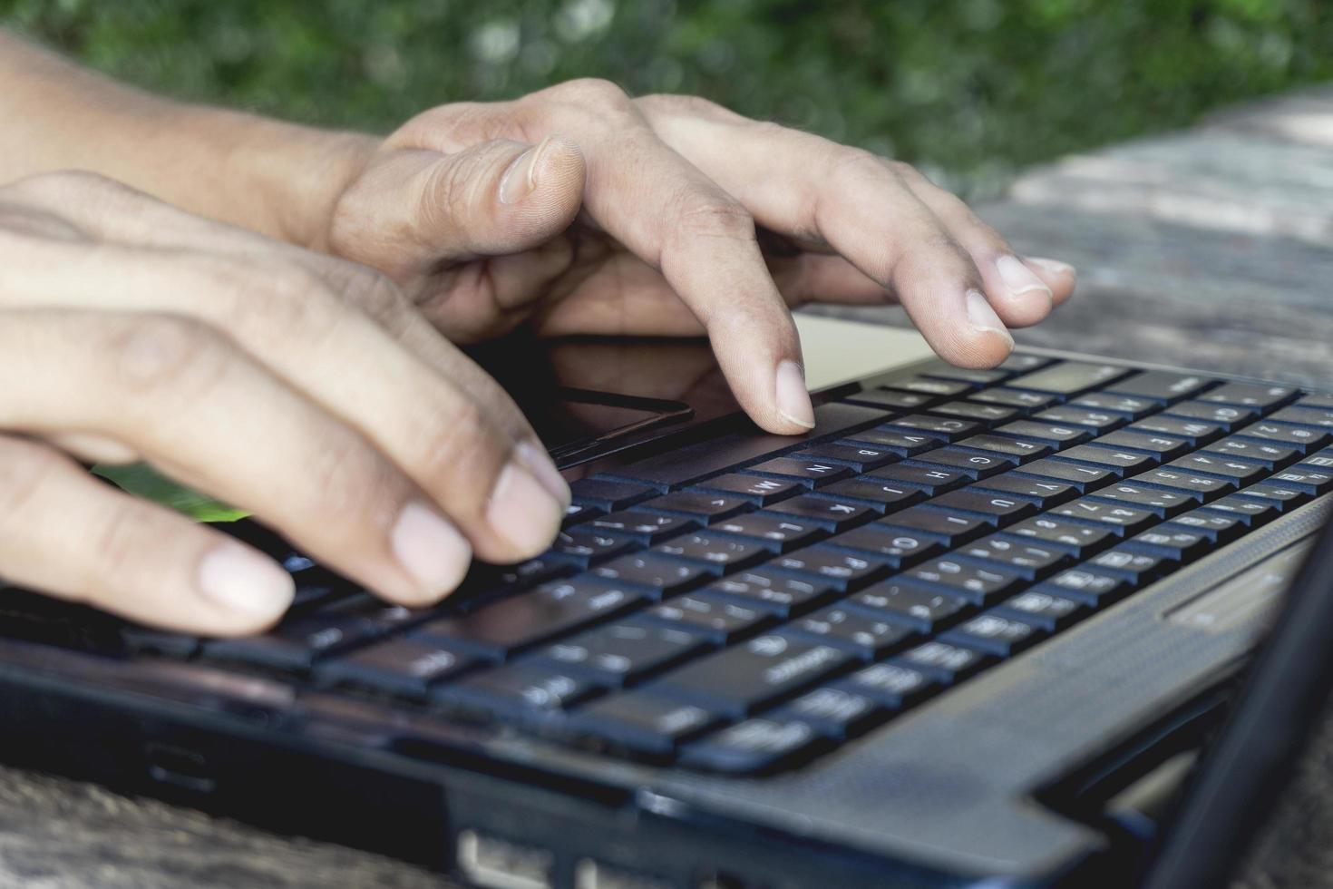 hand persoon werken en gebruiken op een laptopcomputer voor freelance met invoertoetsenbord voor online blogger-baan naar zwarte computer op een houten tafel thuis. foto