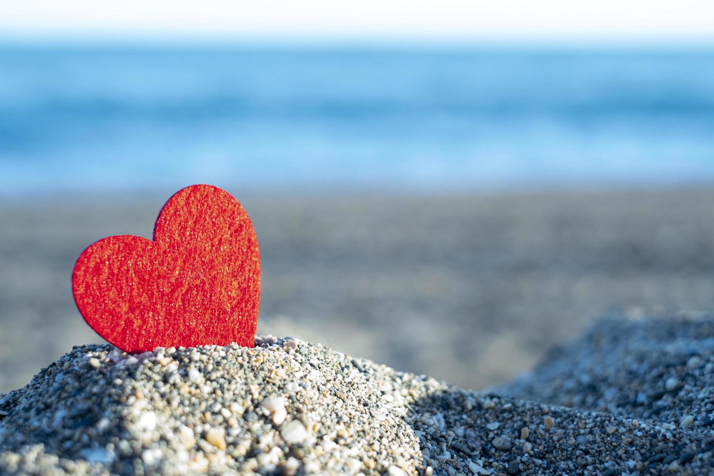 rood hart op een berg zand bij de zee. concept van san valentijn foto