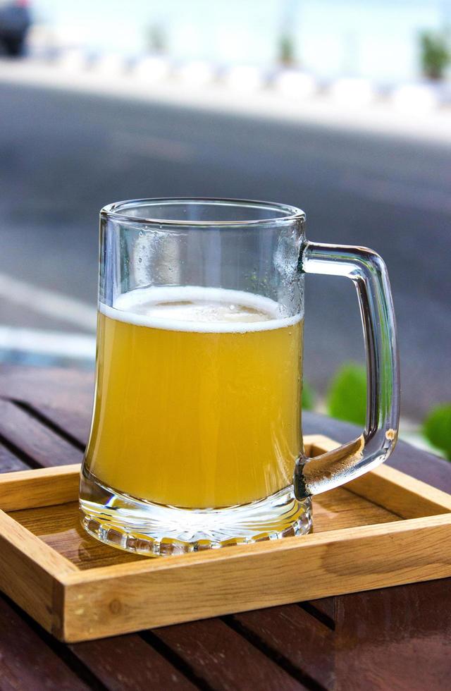 glas bier in houten dienblad op tafel foto