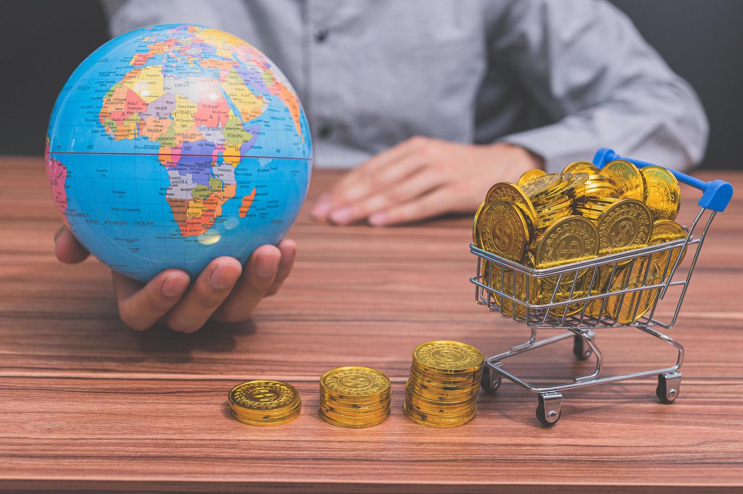 hand met een wereldbol en munten op het bureau foto