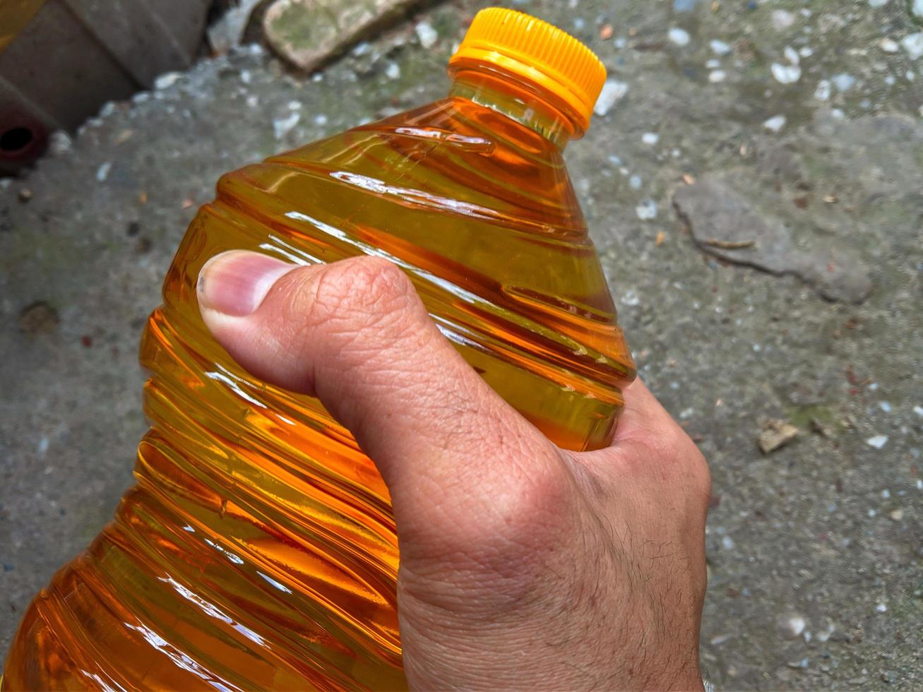 mannetje hand- Holding een fles van Koken olie foto