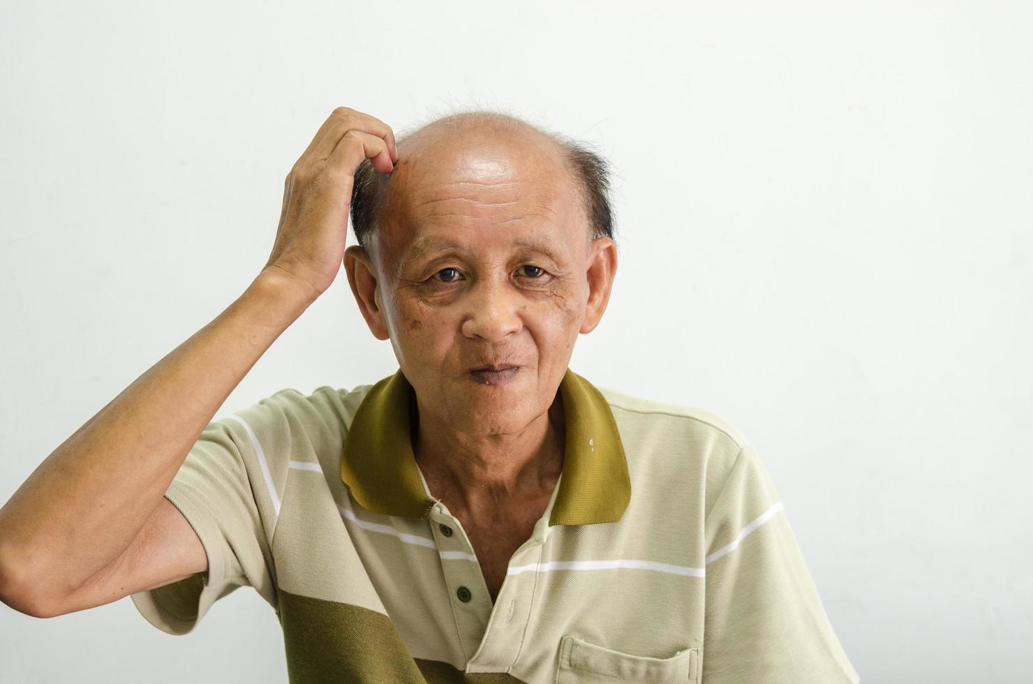 oude Aziatische man zijn hoofd krabben foto