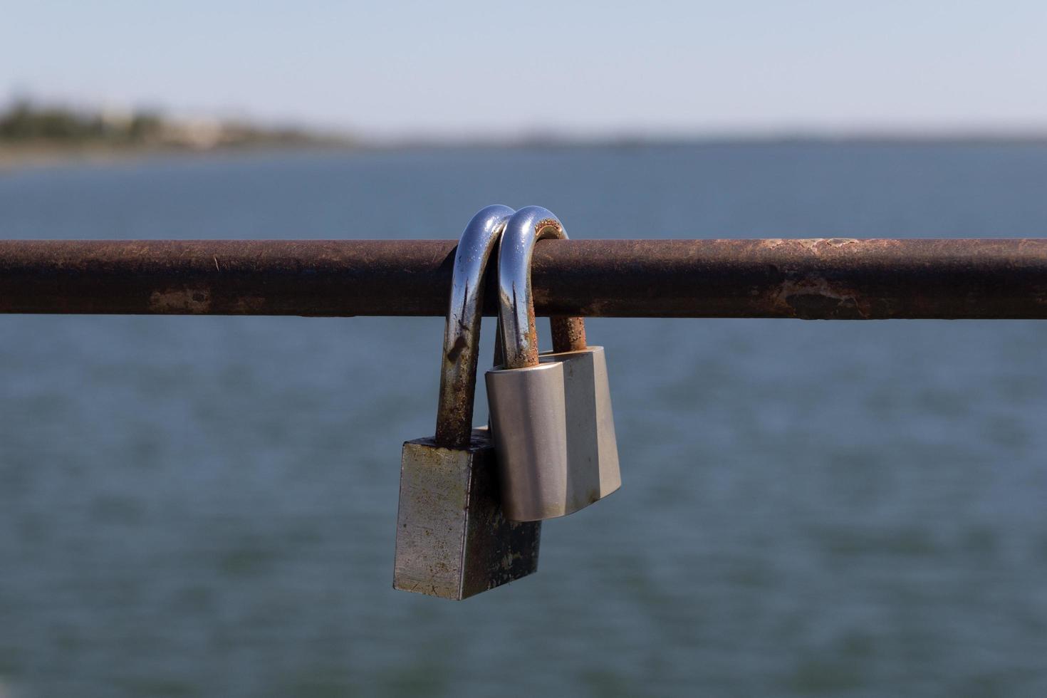 twee hangsloten op een metalen staaf met water en de horizon op de achtergrond foto