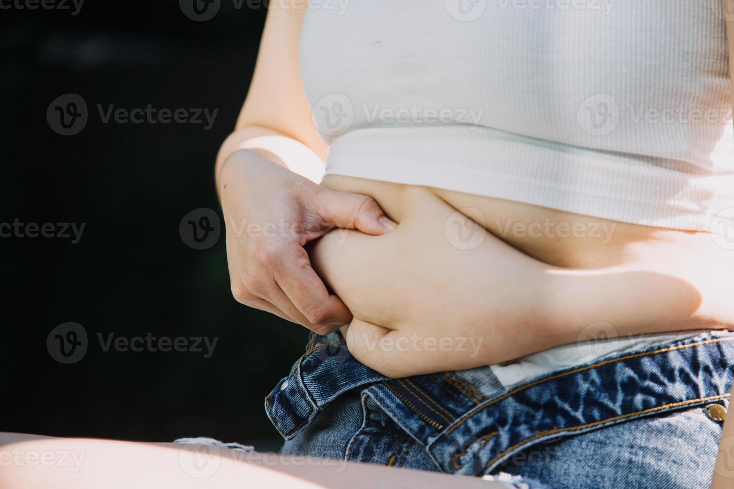 dik vrouw, dik buik, mollig, zwaarlijvig vrouw hand- Holding buitensporig buik dik met meten plakband, vrouw eetpatroon levensstijl concept foto