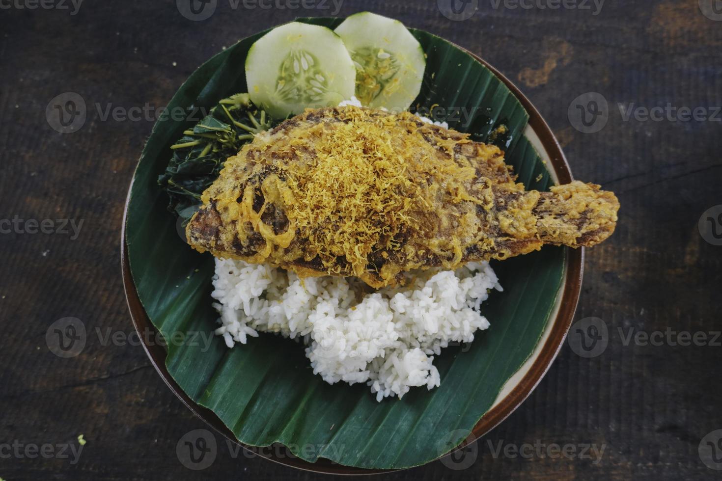 een portret van een gebakken tilapia vis met rijst, groenten of lalapan, en Chili saus of sambal foto