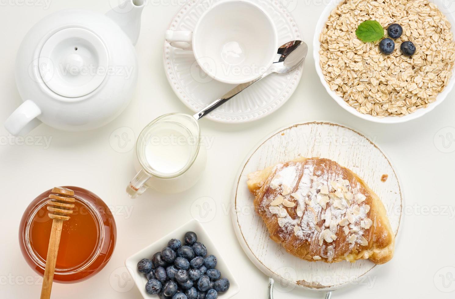 rauw havermout in wit keramisch bord, bosbes, honing Aan wit tafel, ontbijt. top visie foto