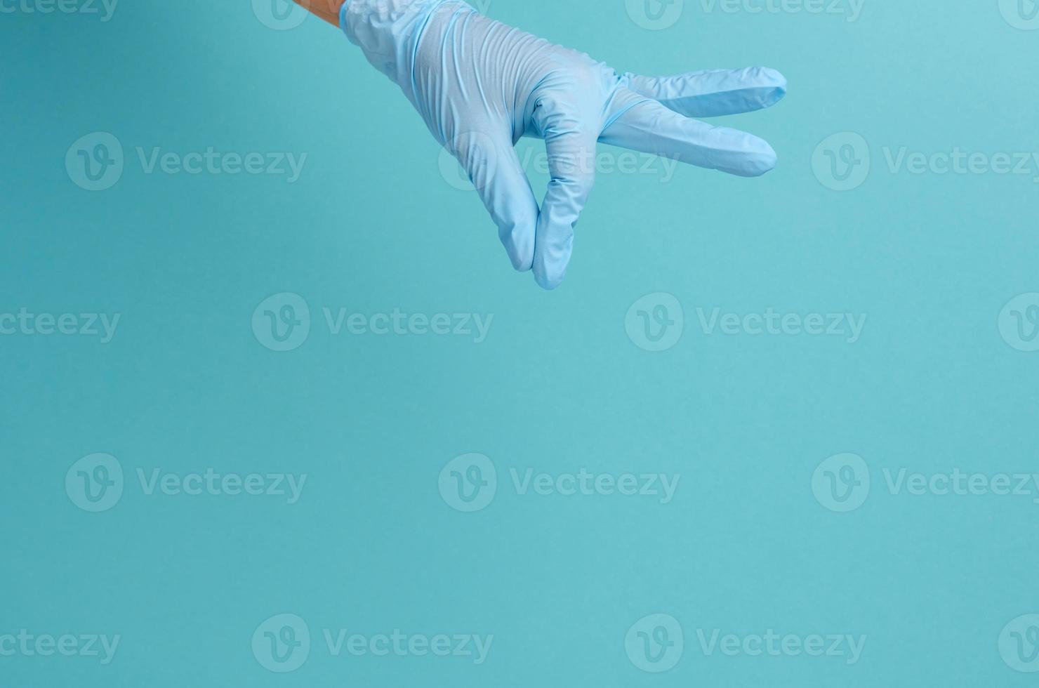 dokter hand- in een blauw medisch handschoen houdt een voorwerp Aan een blauw achtergrond foto