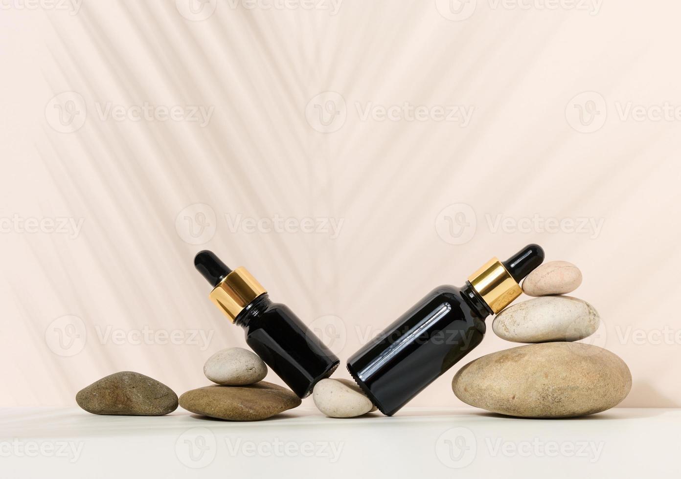 een bruin glas fles met een pipet en een bruin etiket staat Aan een steen. houder voor cosmetica, serum en olie foto