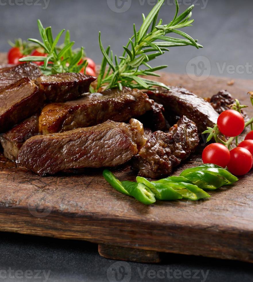 geroosterd stuk van rundvlees biefstuk besnoeiing in stukken Aan een wijnoogst bruin hakken bord. goed gedaan foto