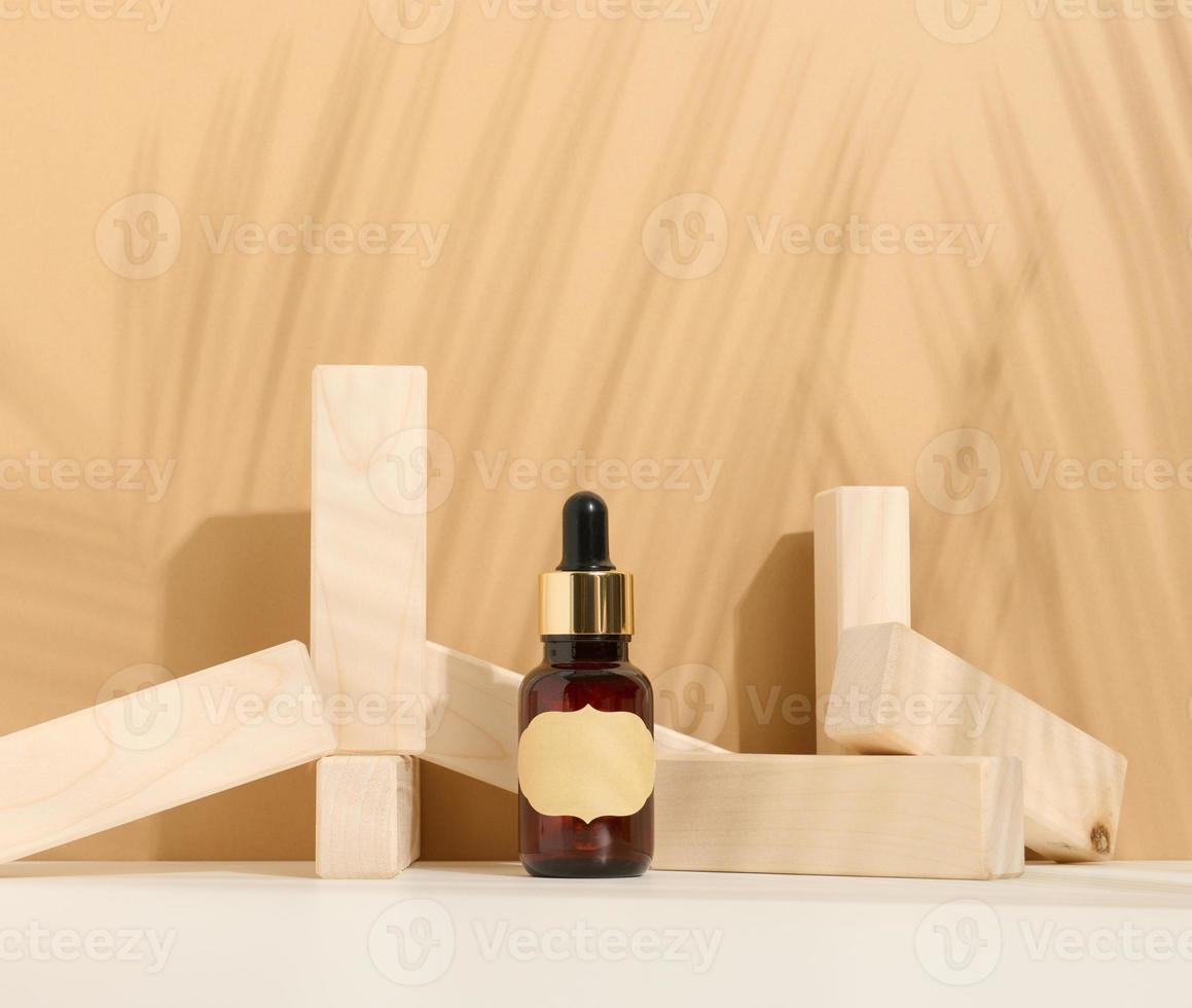 bruin glas fles met een pipet en een bruin etiket staat Aan een bruin achtergrond. houder voor cosmetica, serum en olie. palm blad schaduw foto