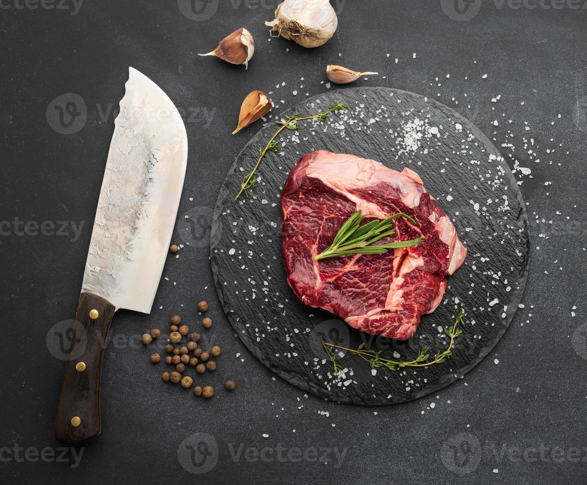 rauw stuk van rundvlees biefstuk met rozemarijn, tijm Aan een zwart tafel, top visie foto