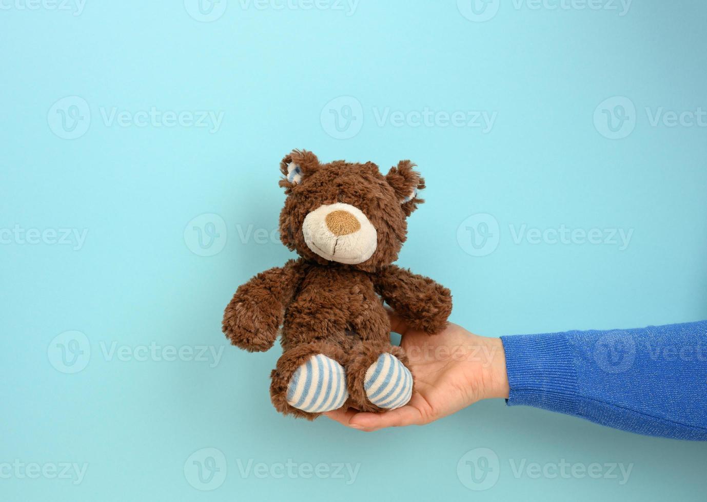vrouw hand- houden een klein bruin speelgoed- teddy beer foto