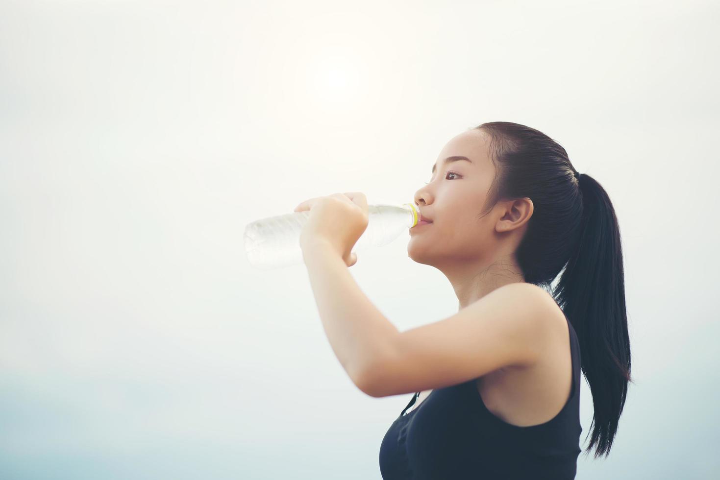 jonge fitness tiener drinkwater na het uitvoeren van oefening foto