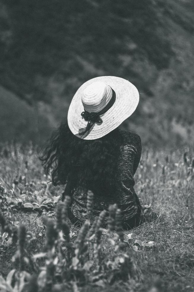 zwart-wit vrouw zittend op de grond dragen zonnehoed foto