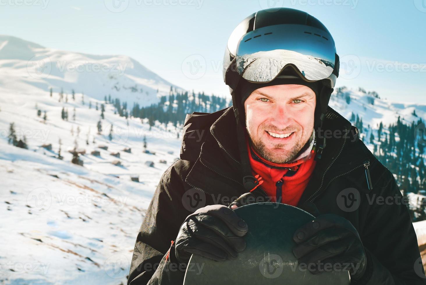 dichtbij omhoog portret Kaukasisch Mens met de reflectie van sneeuwde bergen, wit helling en ski toevlucht. een berg reeks weerspiegeld in de ski masker. portret van Mens Bij de ski toevlucht foto