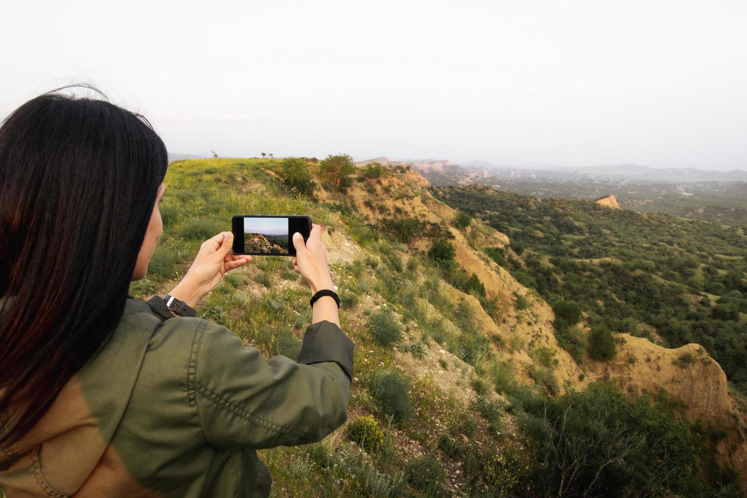 Kaukasisch vrouw houden smartphone nemen foto van mooi natuur buitenshuis Aan vakantie vakantie. gebruik verschillend foto modi Aan scherm kraan Vermelding vastleggen knop