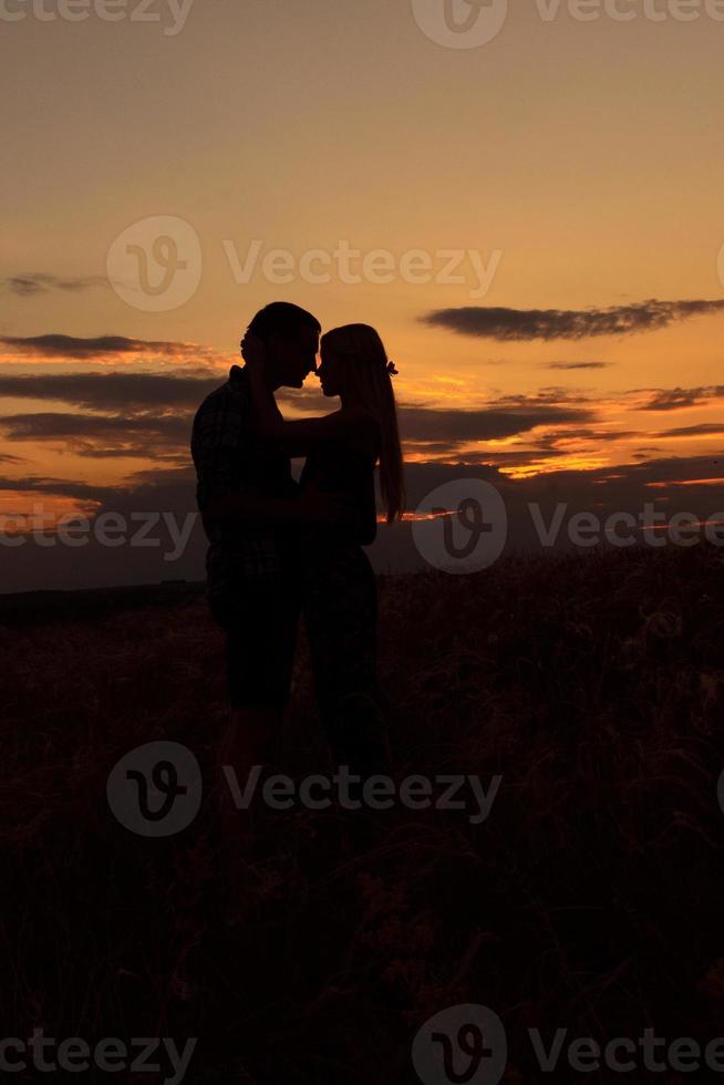 paar in liefde blond meisje in silhouet tegen een zonsondergang foto