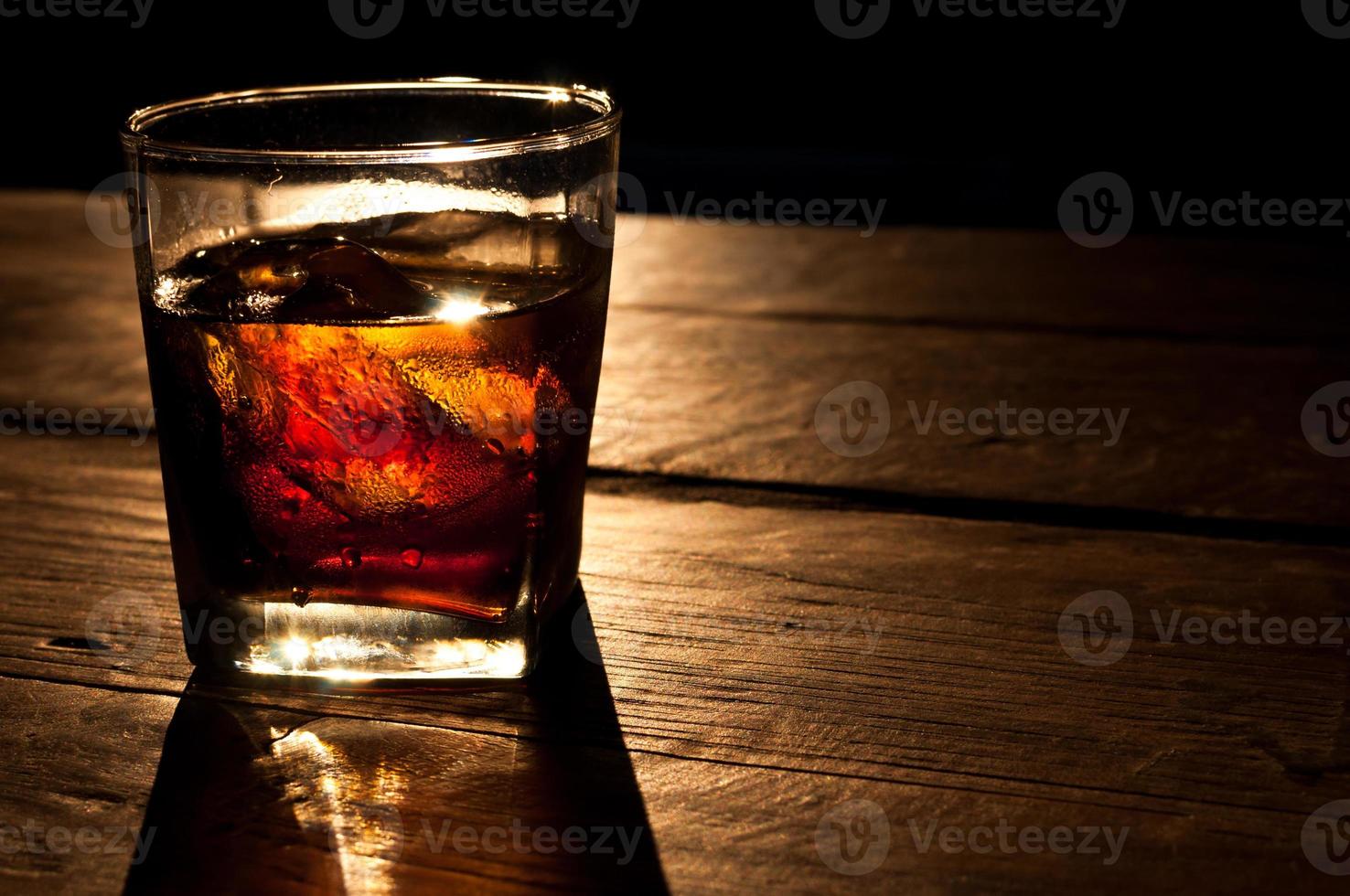 cola met whisky en ijs Aan een houten tafel achtergrond foto