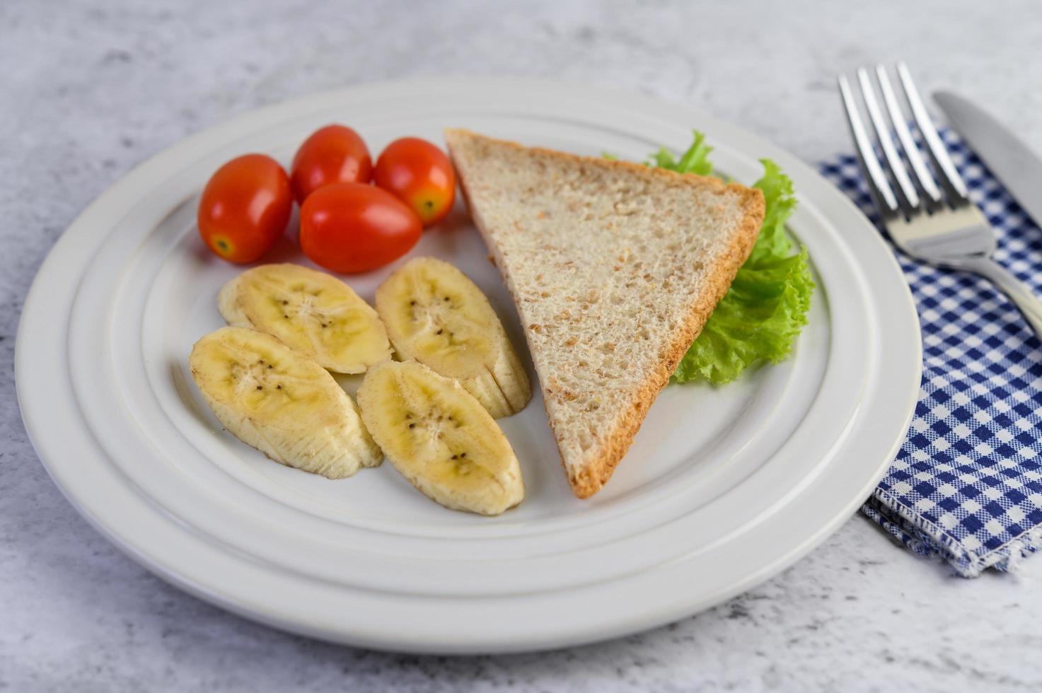 brood met banaan en tomaten op een witte plaat foto
