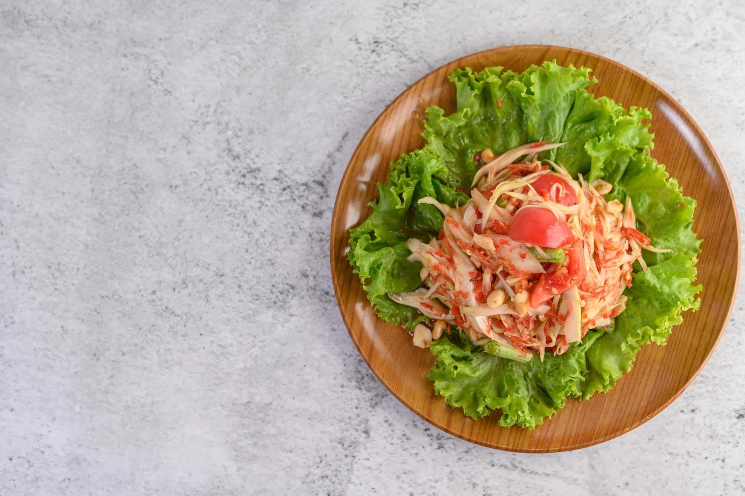 Thaise papajasalade op salade in een houten plaat foto