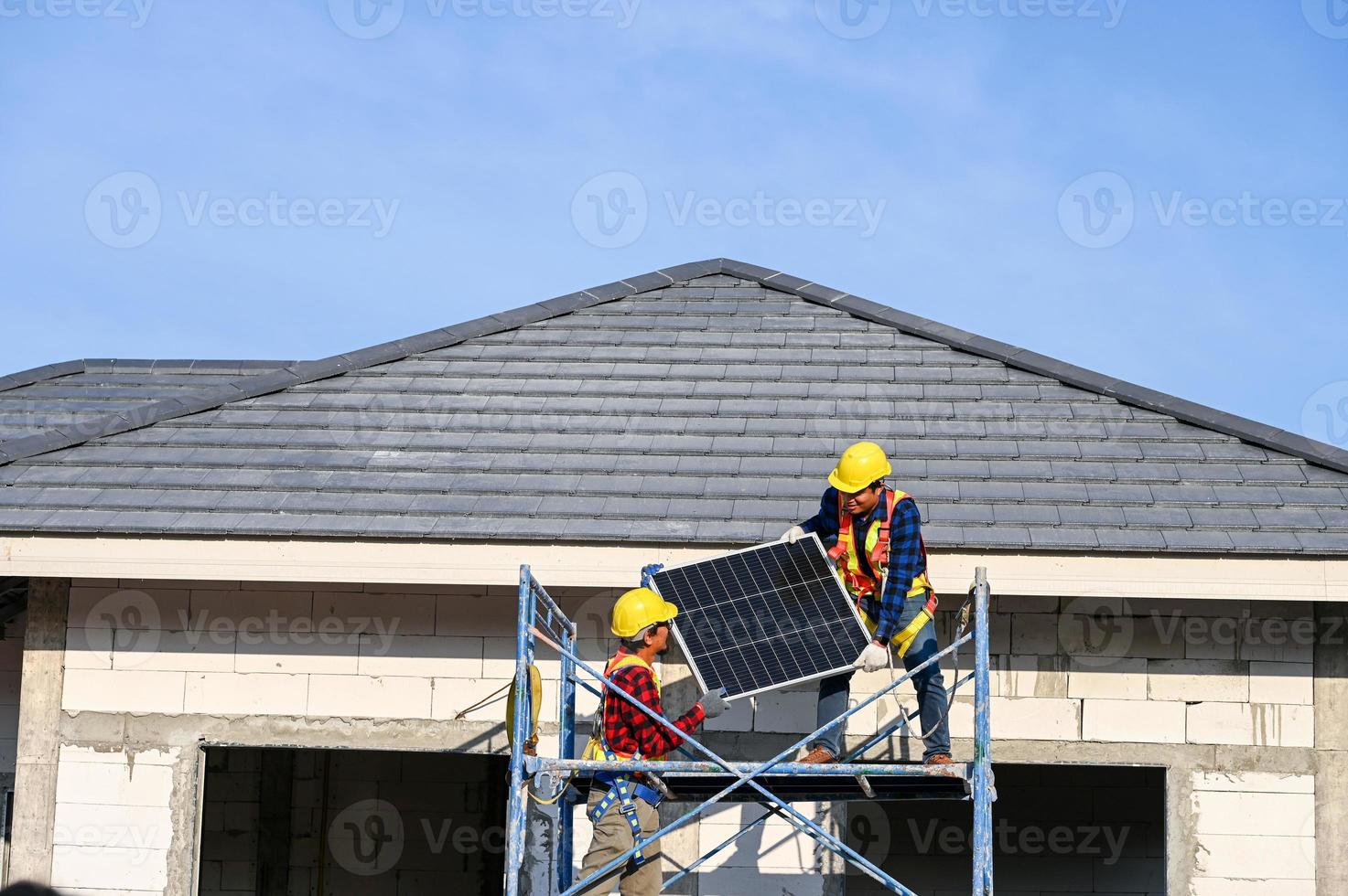 een team van Aziatisch technici installeert zonne- panelen Aan de dak van een huis. dwarsdoorsnede visie van bouwer in helm installeren zonne- paneel systeem concept van hernieuwbaar energie foto