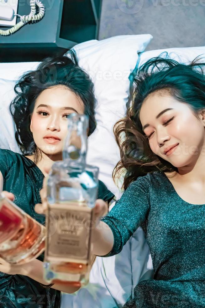 Aziatisch Dames Holding een alcohol fles in hun hand- in de slaapkamer foto