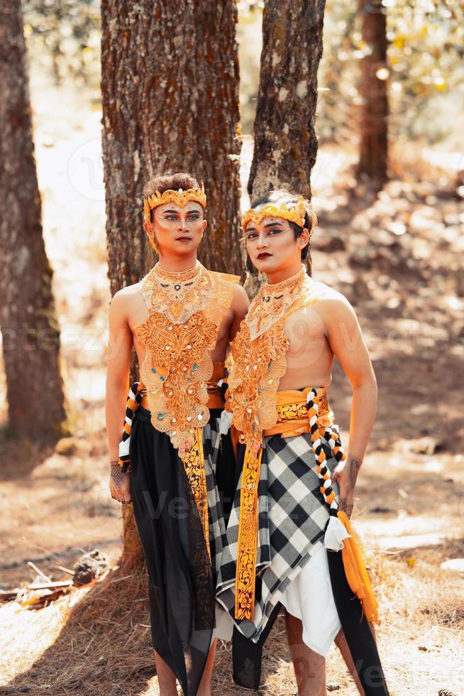twee Aziatisch mannen houding samen met de goud kroon in hun handen en vervelend gestreept kleren foto