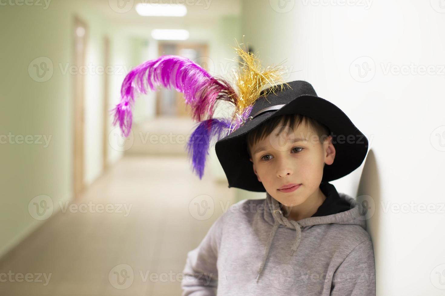 weinig jongen in een theater hoed met veren. jong artiest van de theater studio. foto