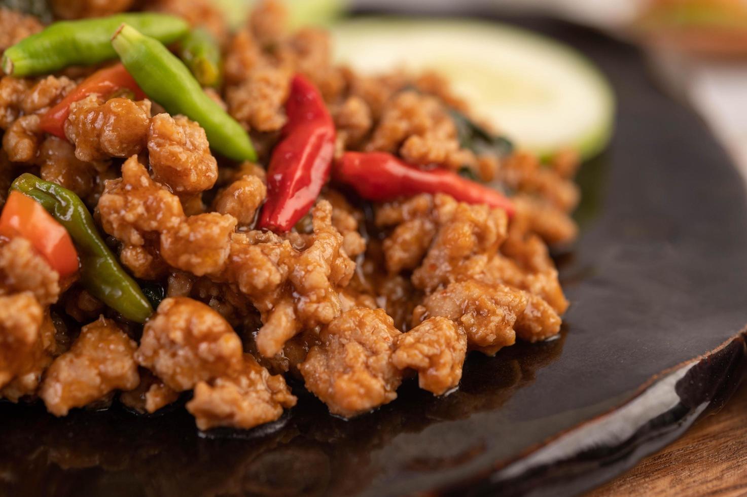 pittige varkensgehakt salade met rijst, chili's en tomaten in een zwarte plaat foto