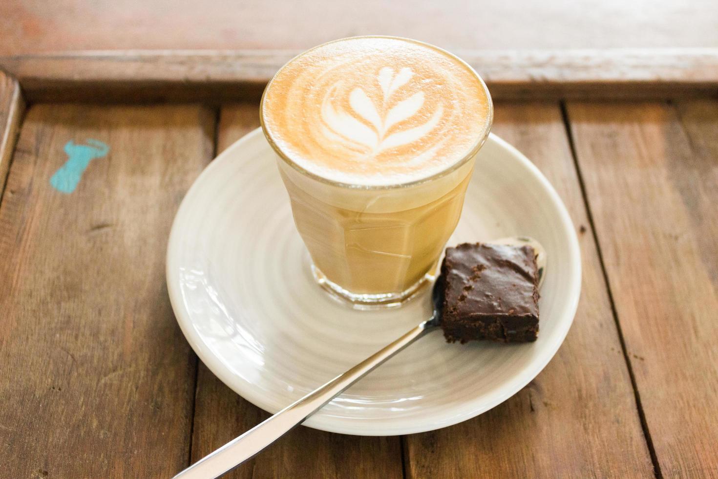 koffie met latte art en brownie op houten plaat foto