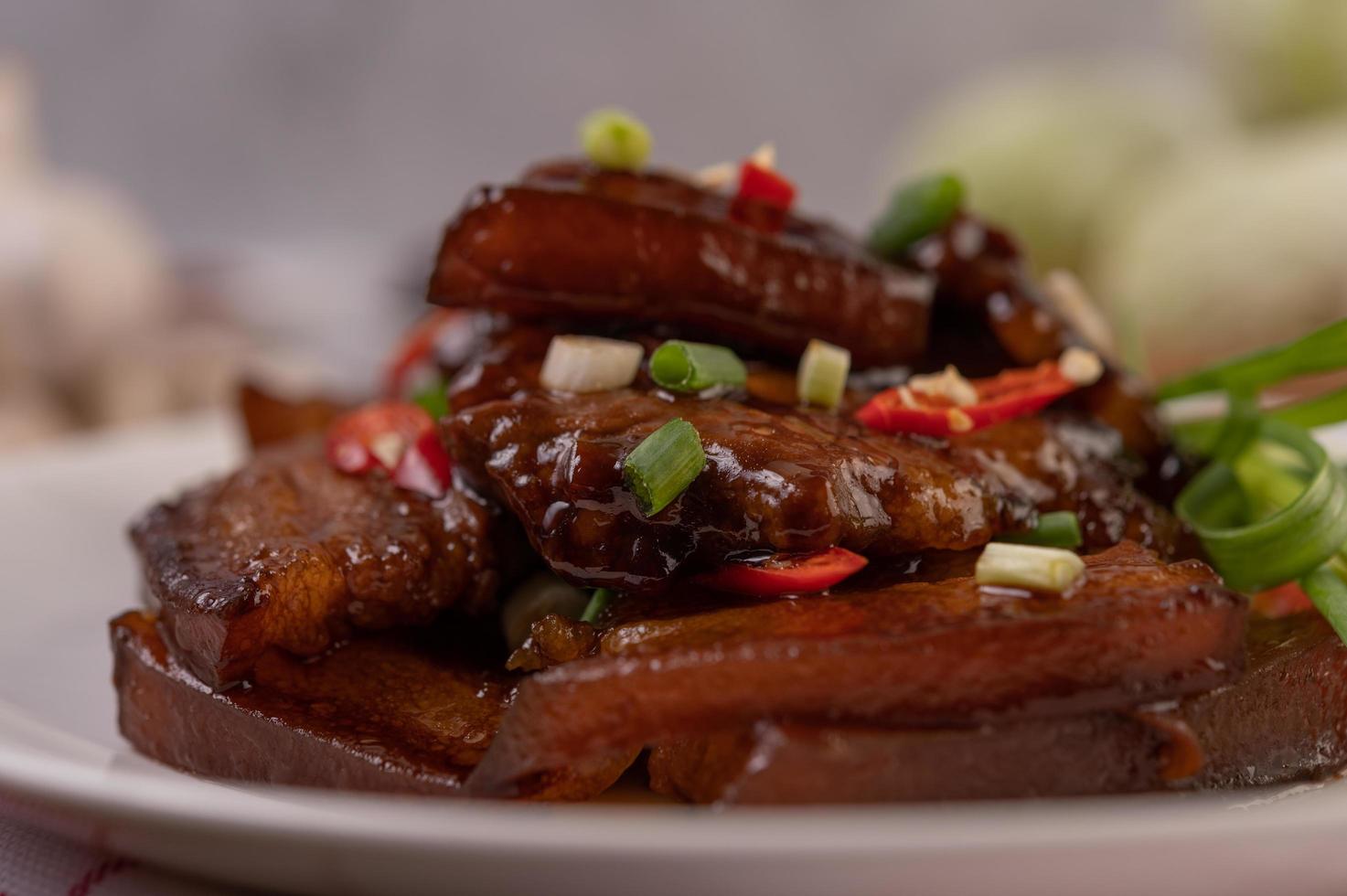 zoet varkensvlees bestrooid met chili en gehakte lente-uitjes foto