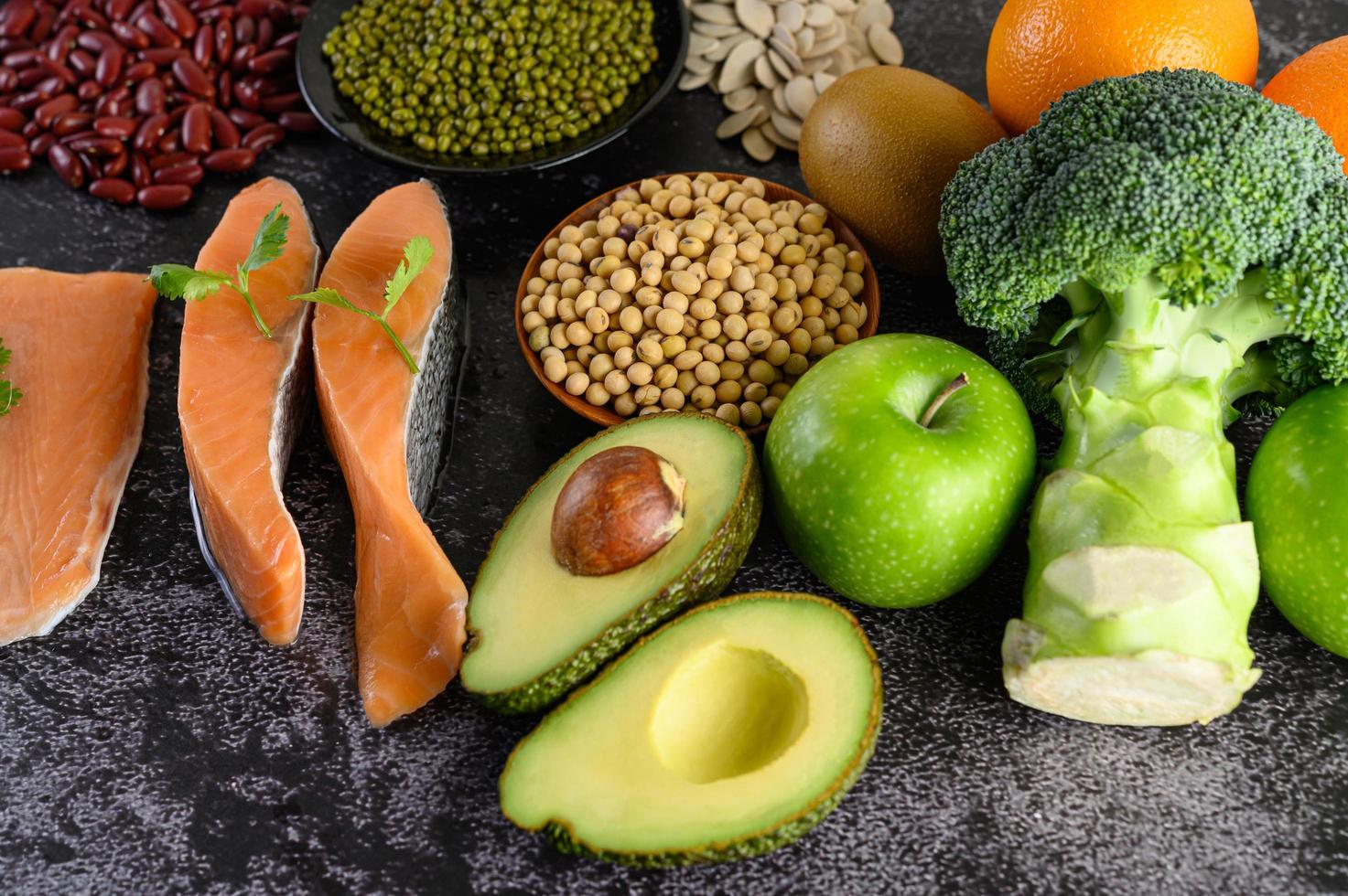 peulvruchten, broccoli, fruit en zalm op een zwarte cementachtergrond foto