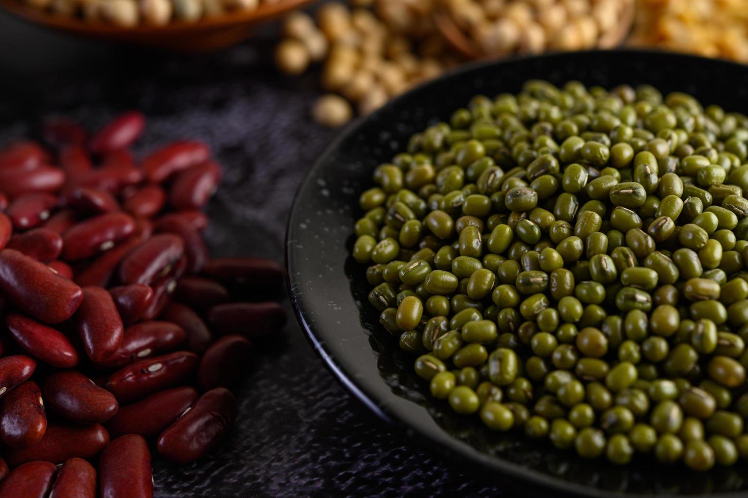 groene bonen en rode bonen op een zwarte cementvloer achtergrond foto