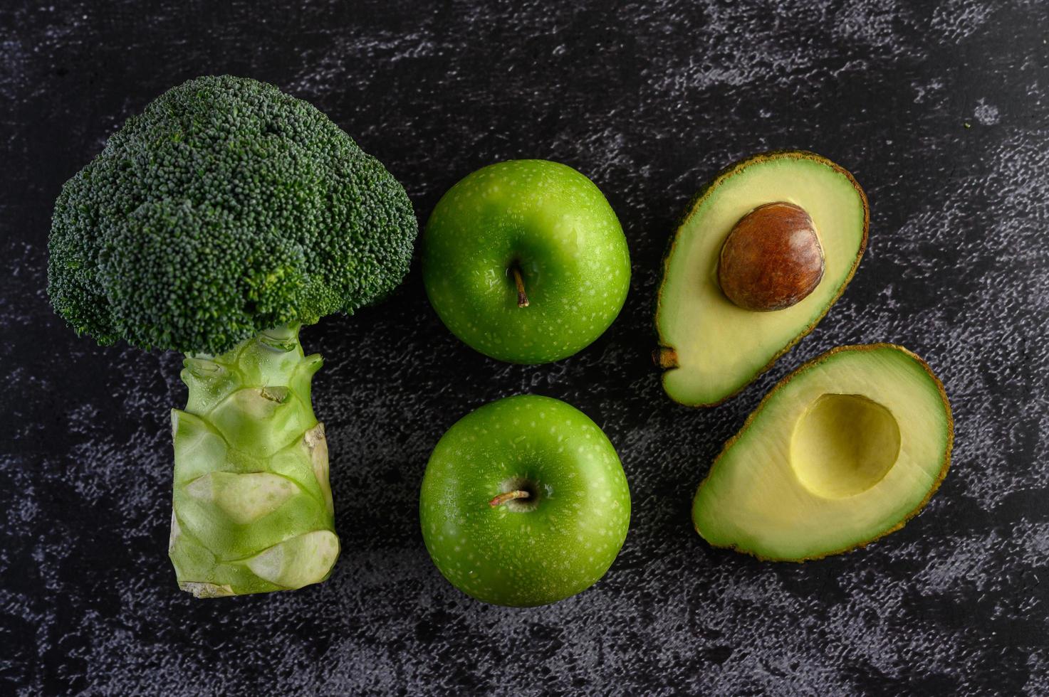 broccoli, appel en avocado op een zwarte cementvloer achtergrond foto