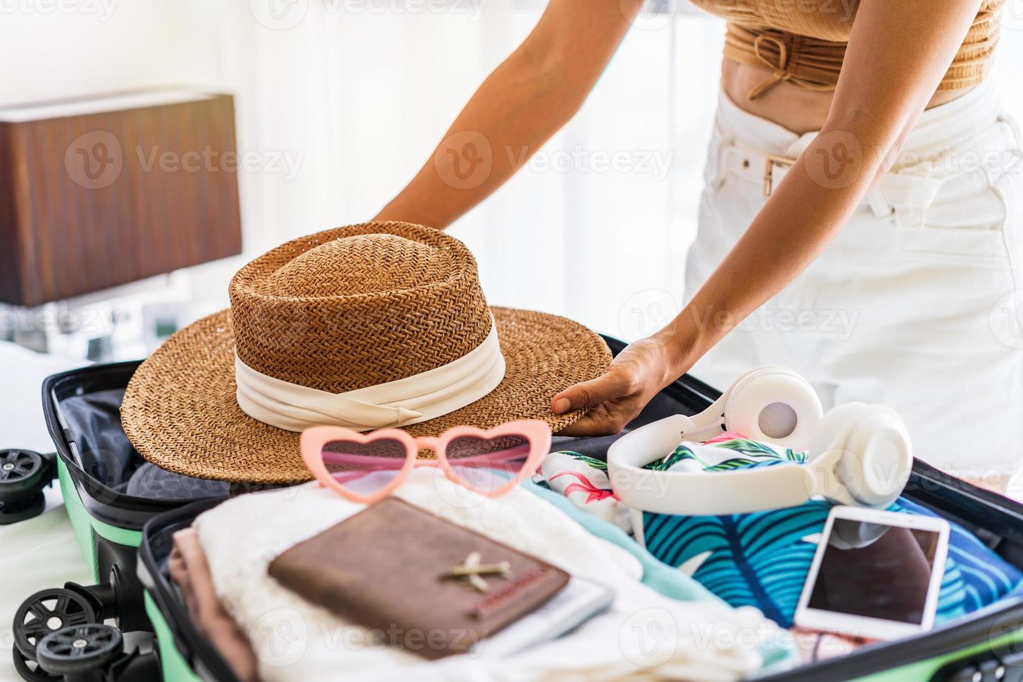 jonge vrouw reiziger zittend op het bed haar koffer inpakken en voorbereiden op reizen op zomervakantie foto