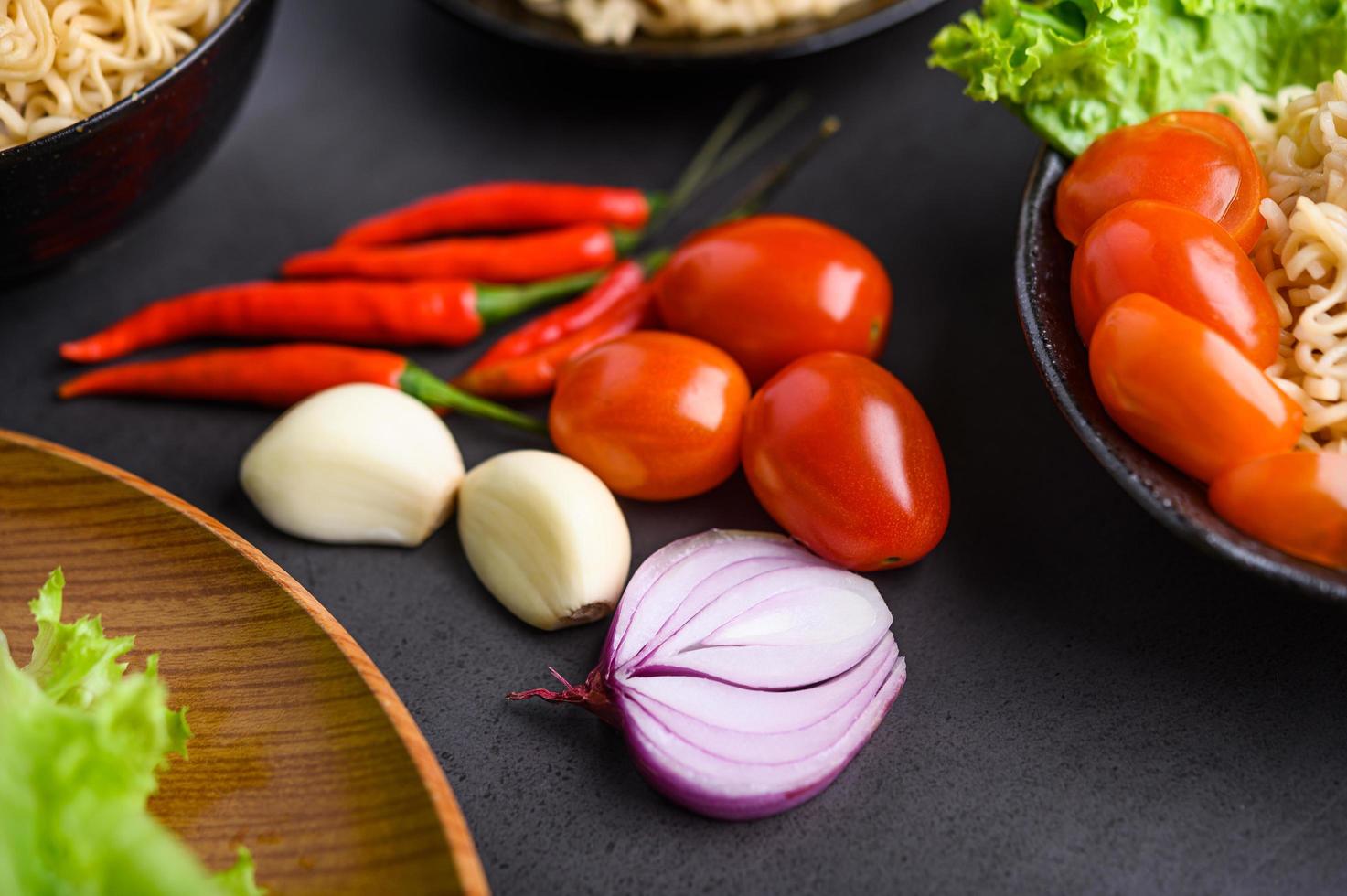 heldere close-up van plakjes rode ui, knoflook, tomaat en paprika foto