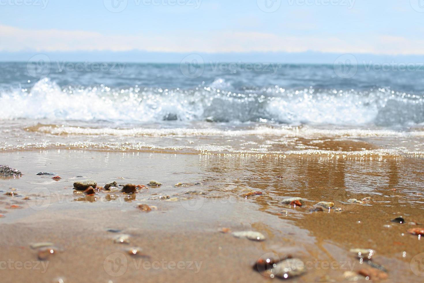 onscherp strand met wazig Golf en nat zand met kiezelsteen Aan blauw lucht. zee, oceaan achtergrond. vakantie buitenshuis en reizen vakantie avontuur concept foto