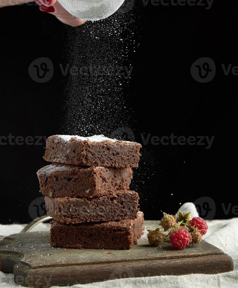 stack van plein gebakken brownie chocola taart plakjes besprenkeld met wit suiker van een ijzer zeef foto