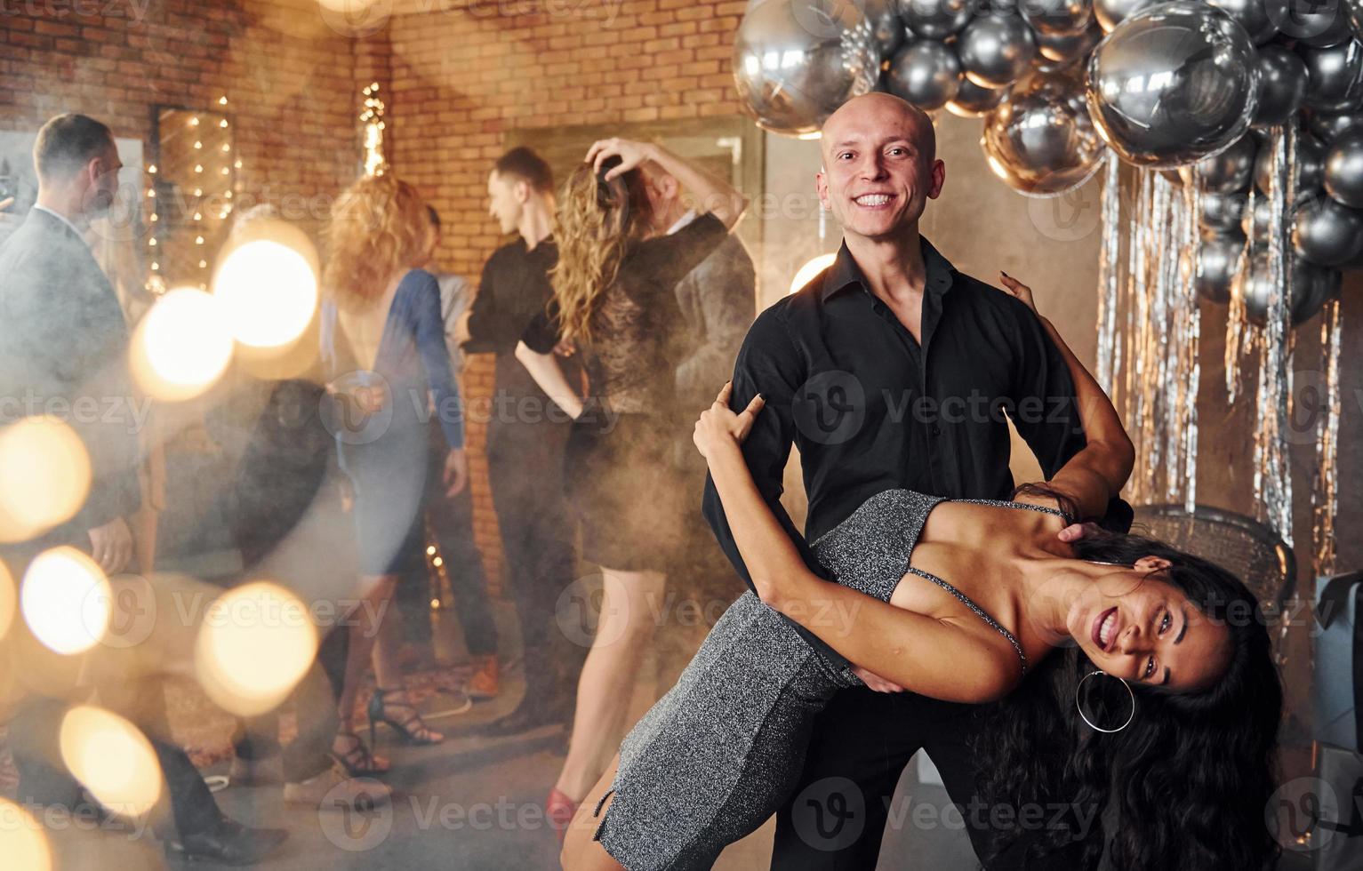 jong paar dansen tegen hun vrienden in Kerstmis versierd kamer en vieren nieuw jaar foto