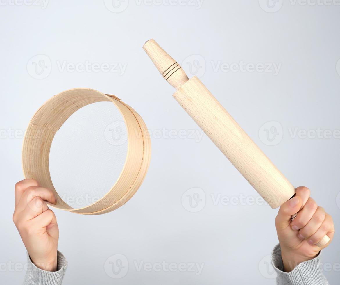 vrouw handen houden ronde houten zeef voor meel en rollend pin foto