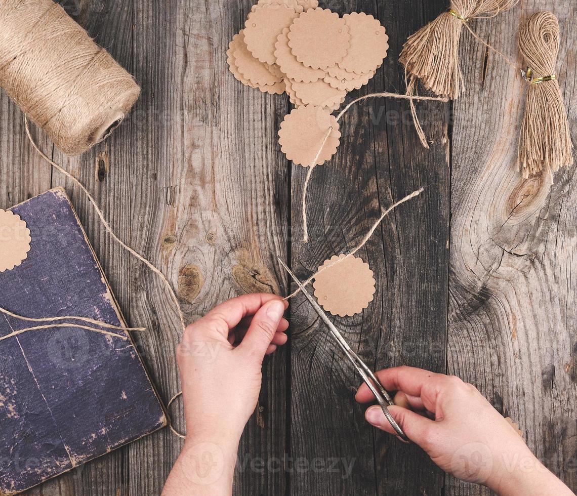 twee vrouw handen en papier tags met een bruin touw Aan een grijs houten tafel foto