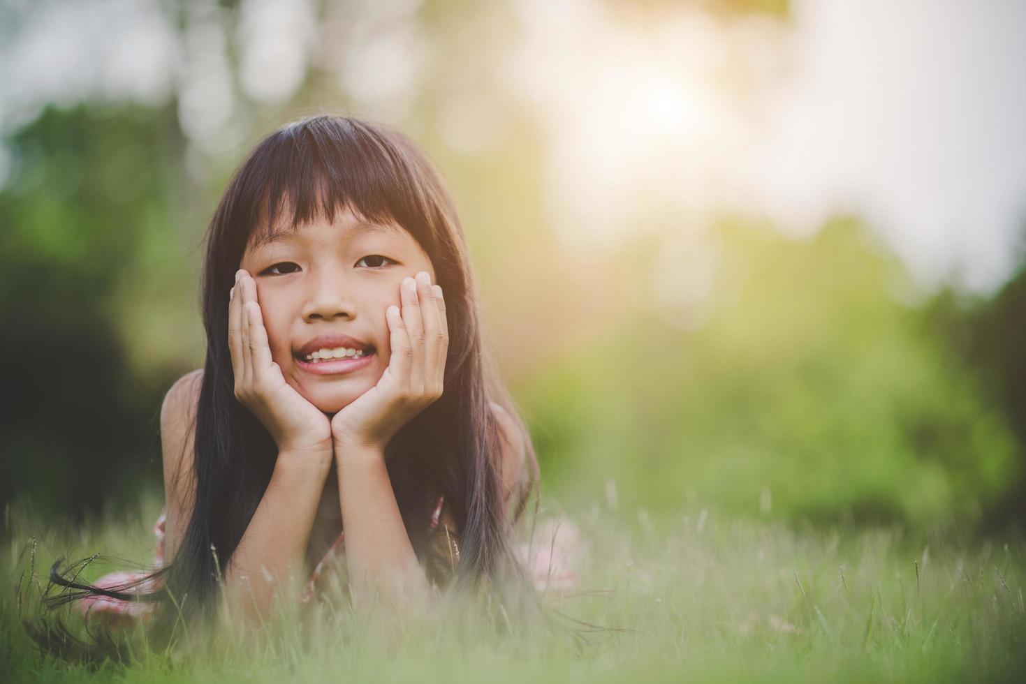 klein meisje comfortabel op het gras liggen en glimlachen foto