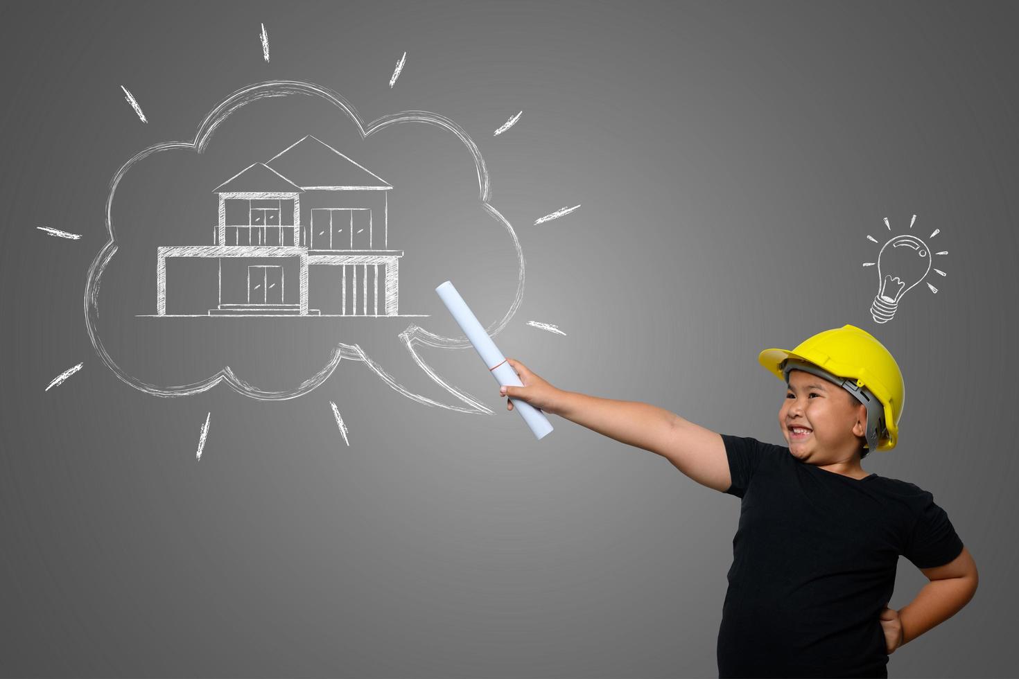 jonge jongen met een gele ingenieurshoed en huisplanideeën op een schoolbord foto