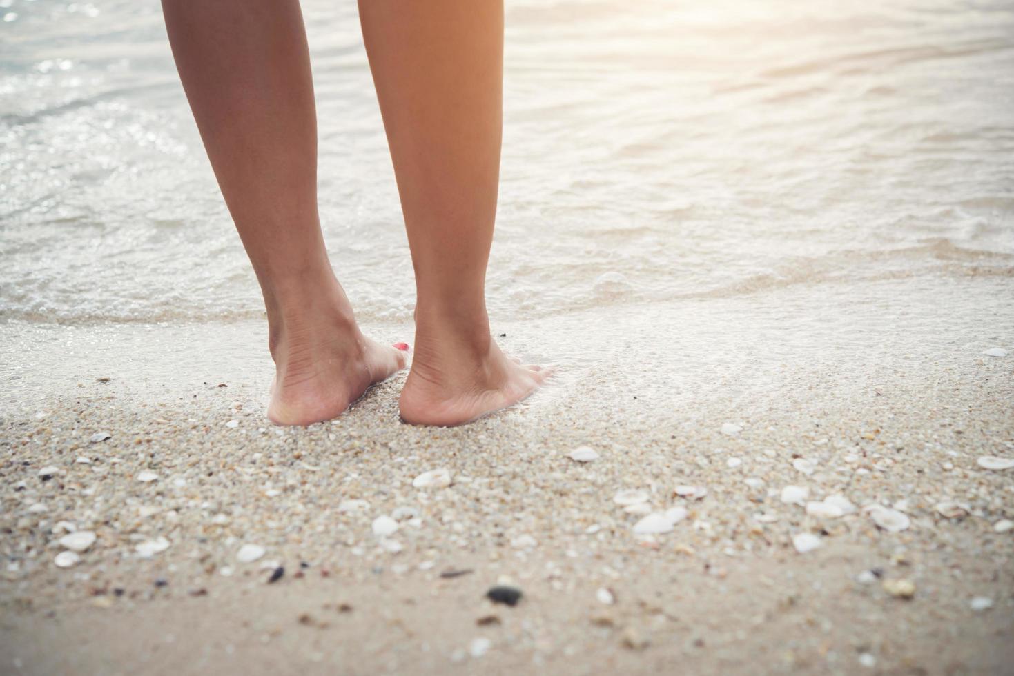 jonge vrouw stond op het strand met blote voeten foto