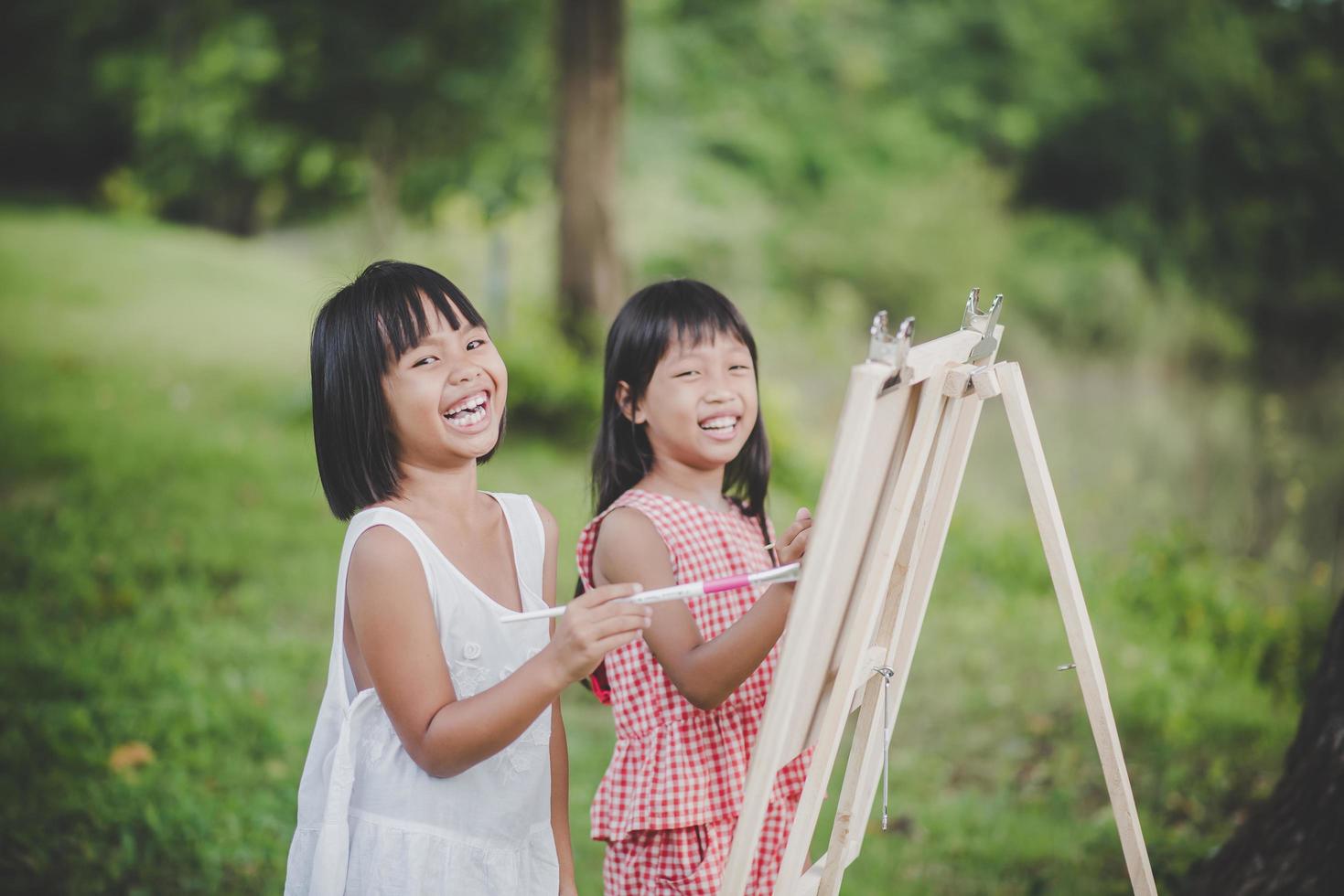 twee kleine meisjesschilders die kunst in het park trekken foto